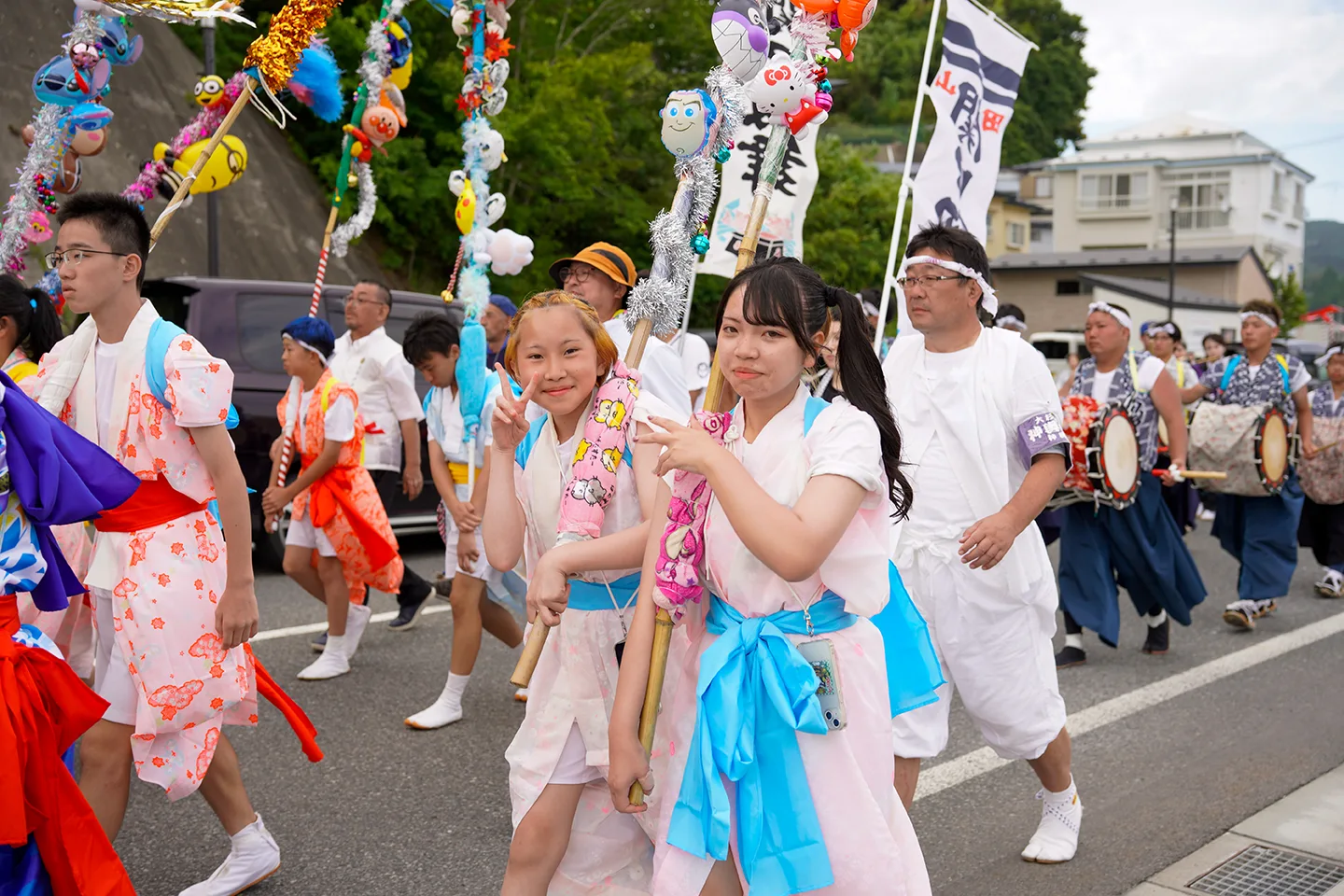 山田祭りで飾り棒を担いで行進する法被姿の女の子たちと太鼓の行列