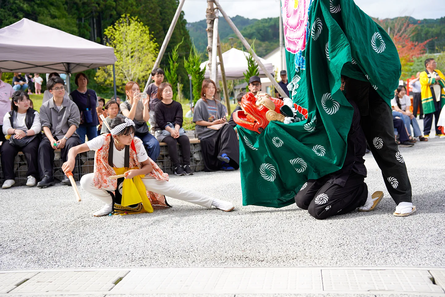 山田祭りで獅子舞と向かい合いバチを構える衣装姿の少女
