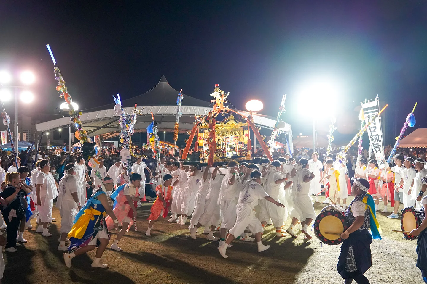 山田祭りの夜、飾り棒に囲まれ会場を練り歩く神輿と白装束の担ぎ手
