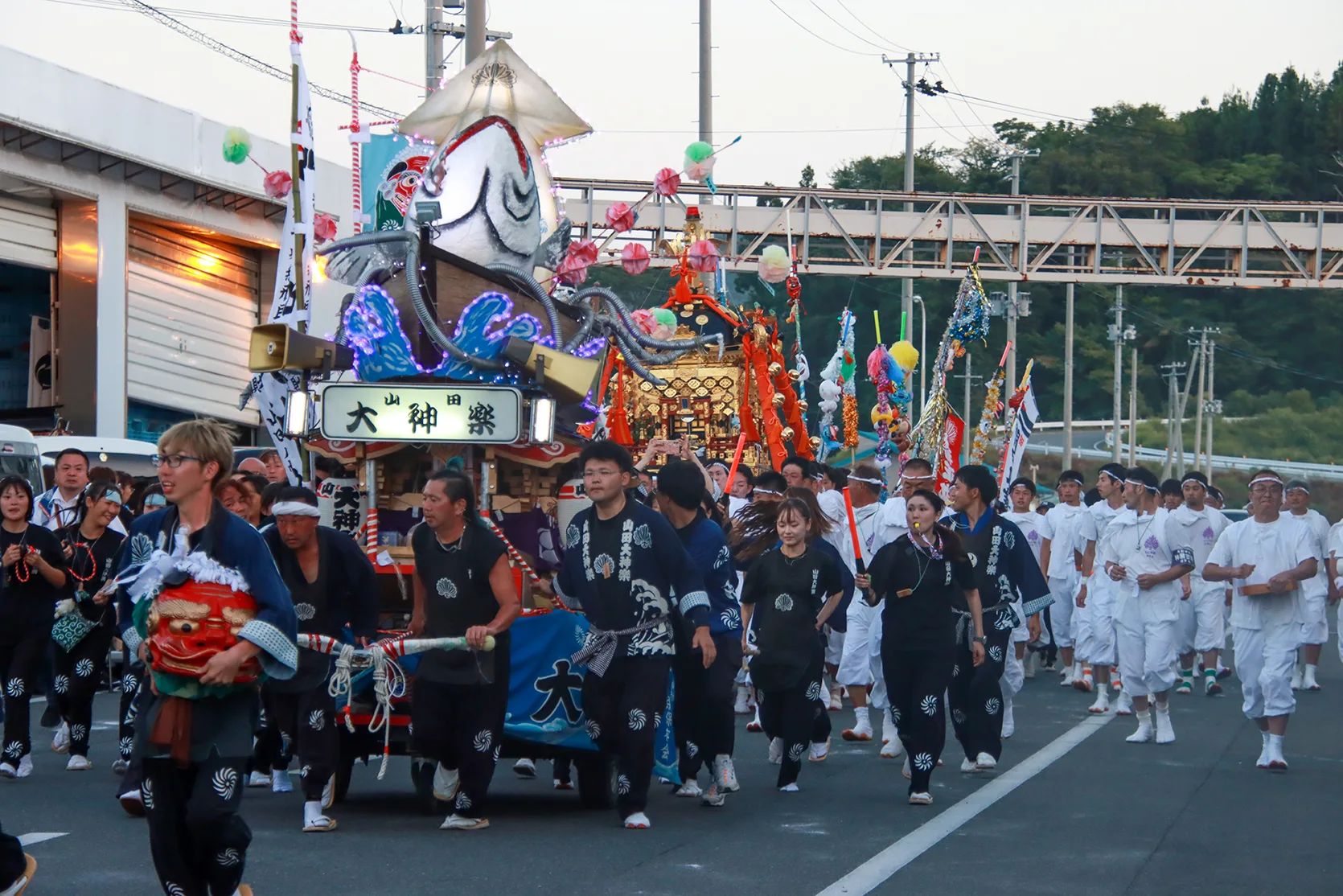 夕暮れの山田祭りを進む山田大神楽の山車と権現頭を抱えた行列