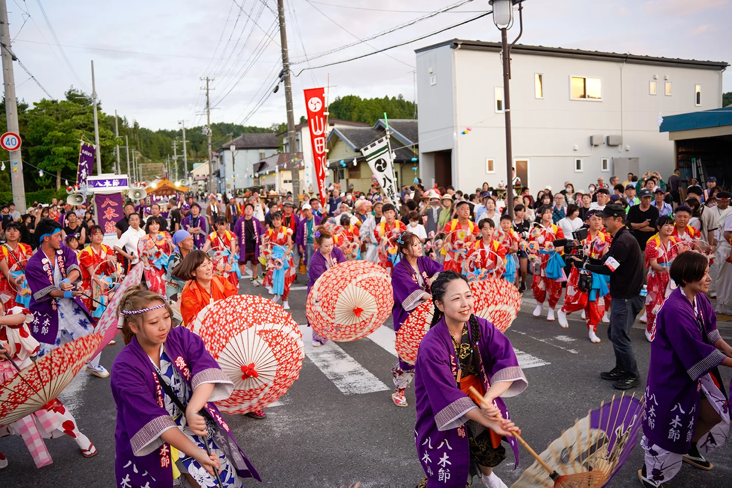 夕暮れの山田祭りで番傘を回して踊る八木節の踊り手たち