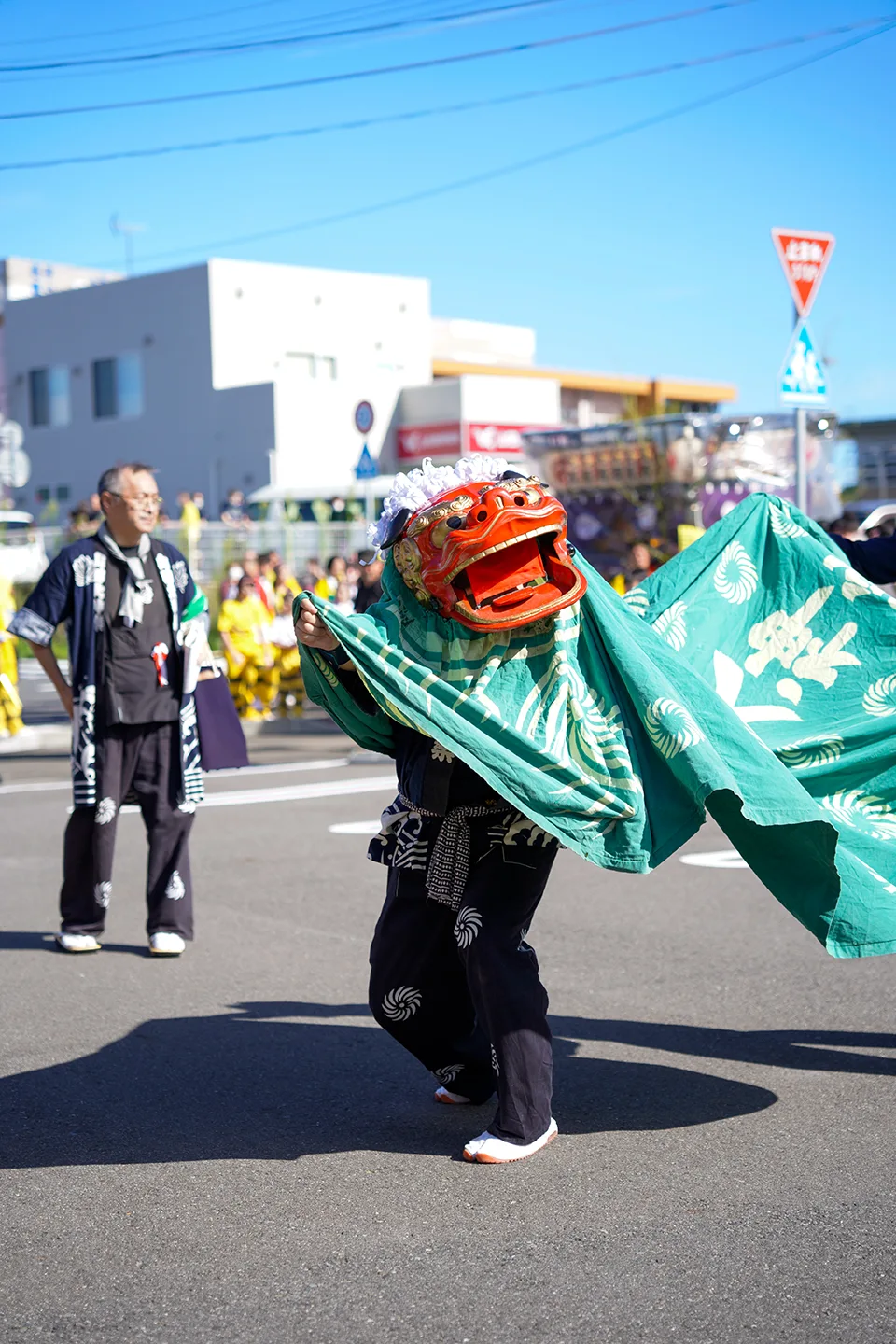 山田祭りの路上で緑の胴幕を翻して舞う獅子舞