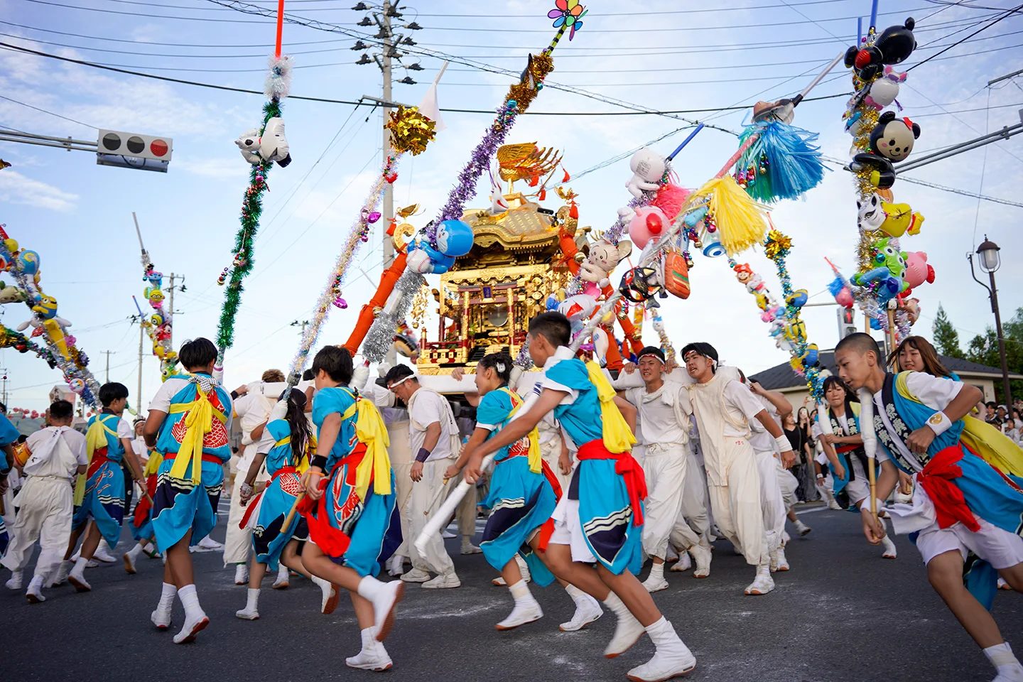 山田祭りで飾り棒に囲まれながら神輿を担いで駆ける子どもたち