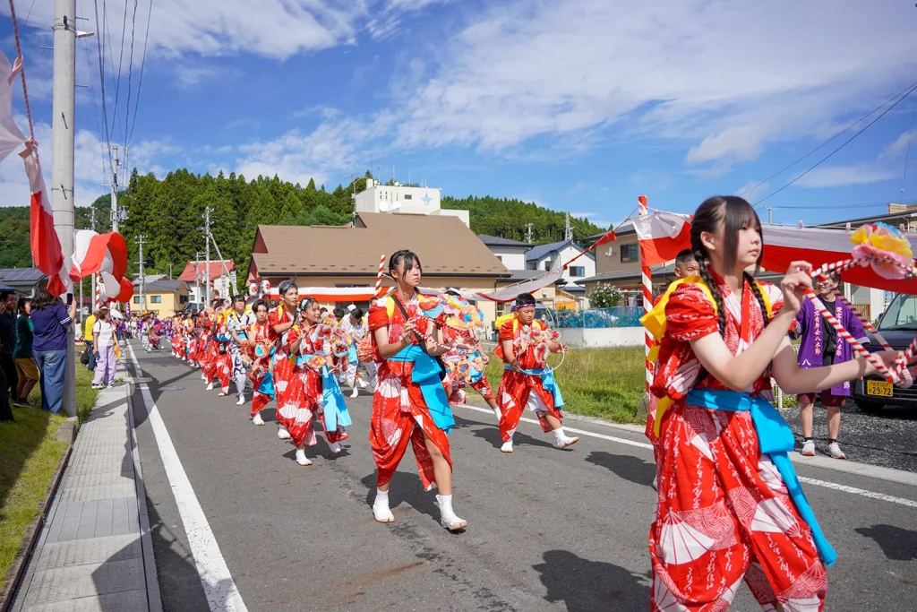 山田祭りの沿道を赤い衣装で踊り歩く子どもたちの手踊り行列