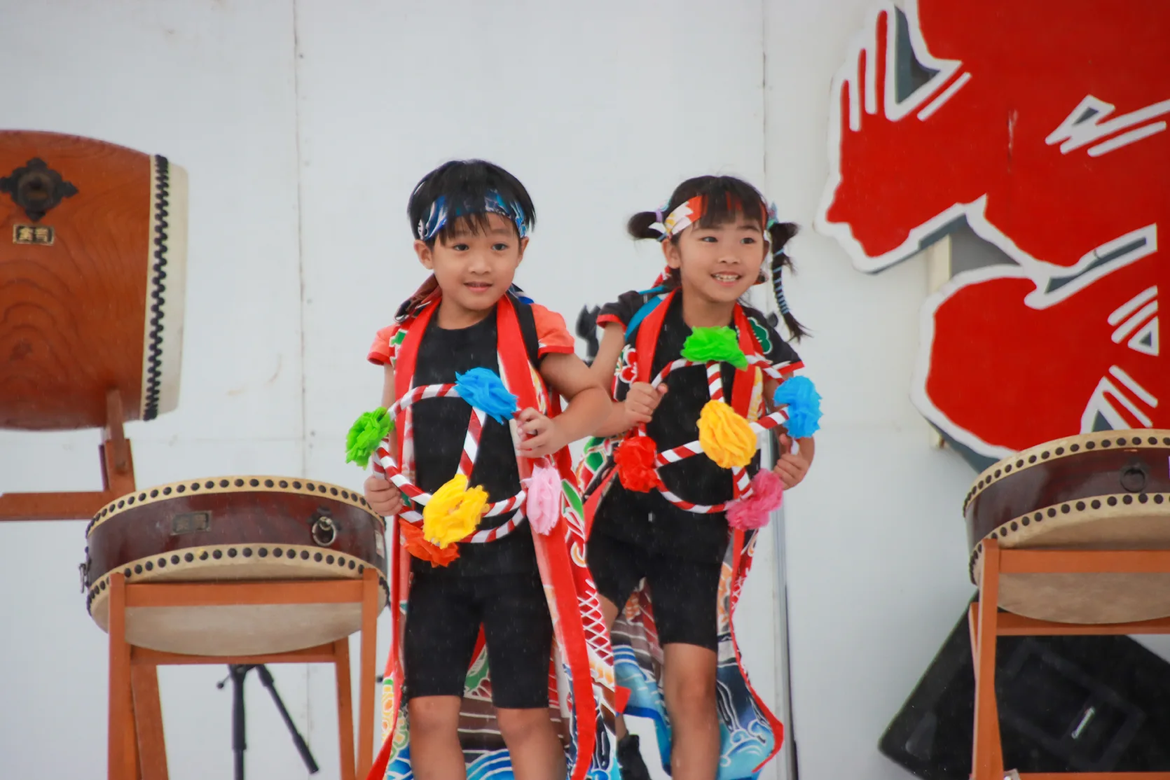 山田祭りのステージで花輪を持って踊る小さな子どもたち