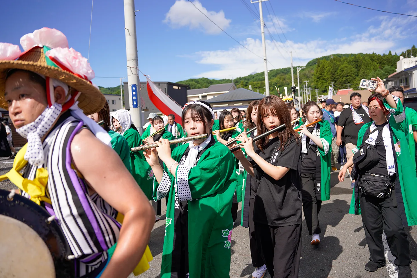 山田祭りで笛を吹きながら行進する緑の法被姿のお囃子の一行